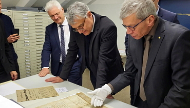 Staatssekretär Arne Braun begutachtet im Kartenmagazin die die älteste im Staatsarchiv verwahrte Urkunde, eine Bleibulle Papst Urbans II. von 1079.
