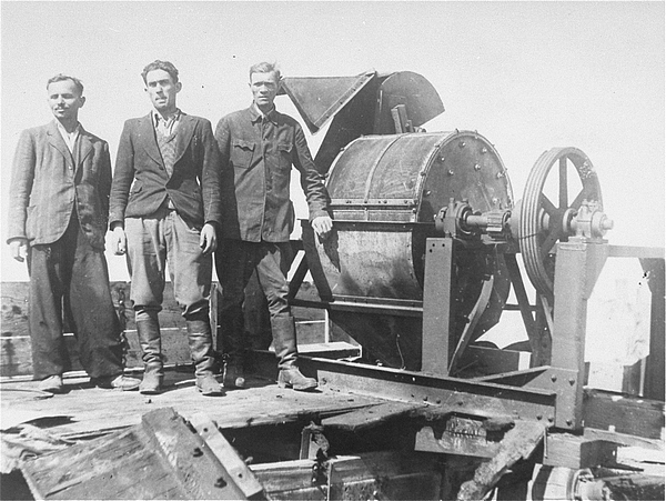 Jüdische Gefangene des Sonderkommandos 1005 vor einer Knochenmahlmaschine im Konzentrationslager Janowska