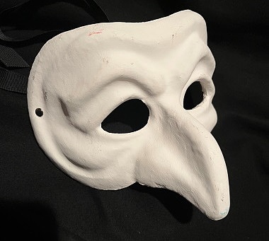 Das Bild zeigt eine weiße Theater-Maske vor schwarzem Hintergrund.